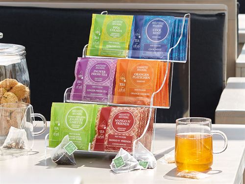Expositor acrílico de tés organizando varios sobres de té en un entorno elegante, ideal para restaurantes y oficinas.