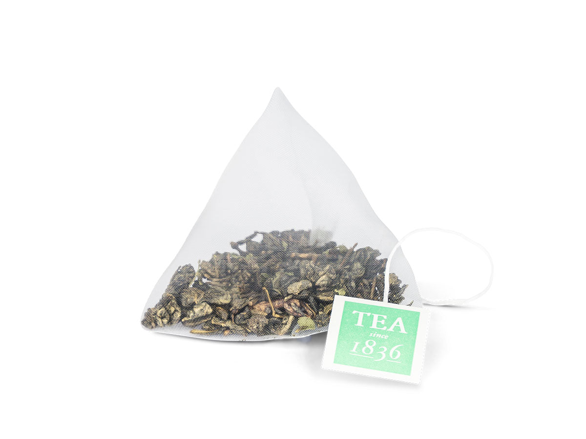 Té verde con sabor a menta en pirámides, bolsita de té con ingredientes frescos y aromáticos.