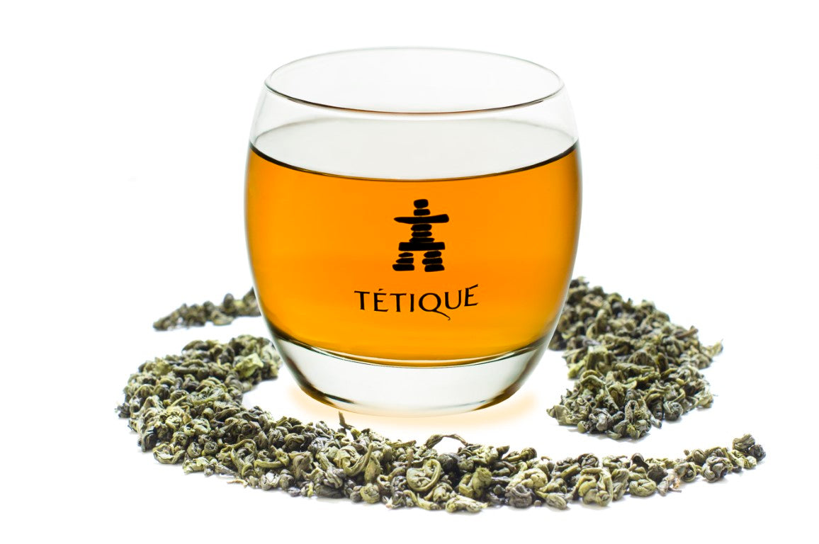 Té Verde Gunpowder biológico en un vaso transparente con hojas secas alrededor.