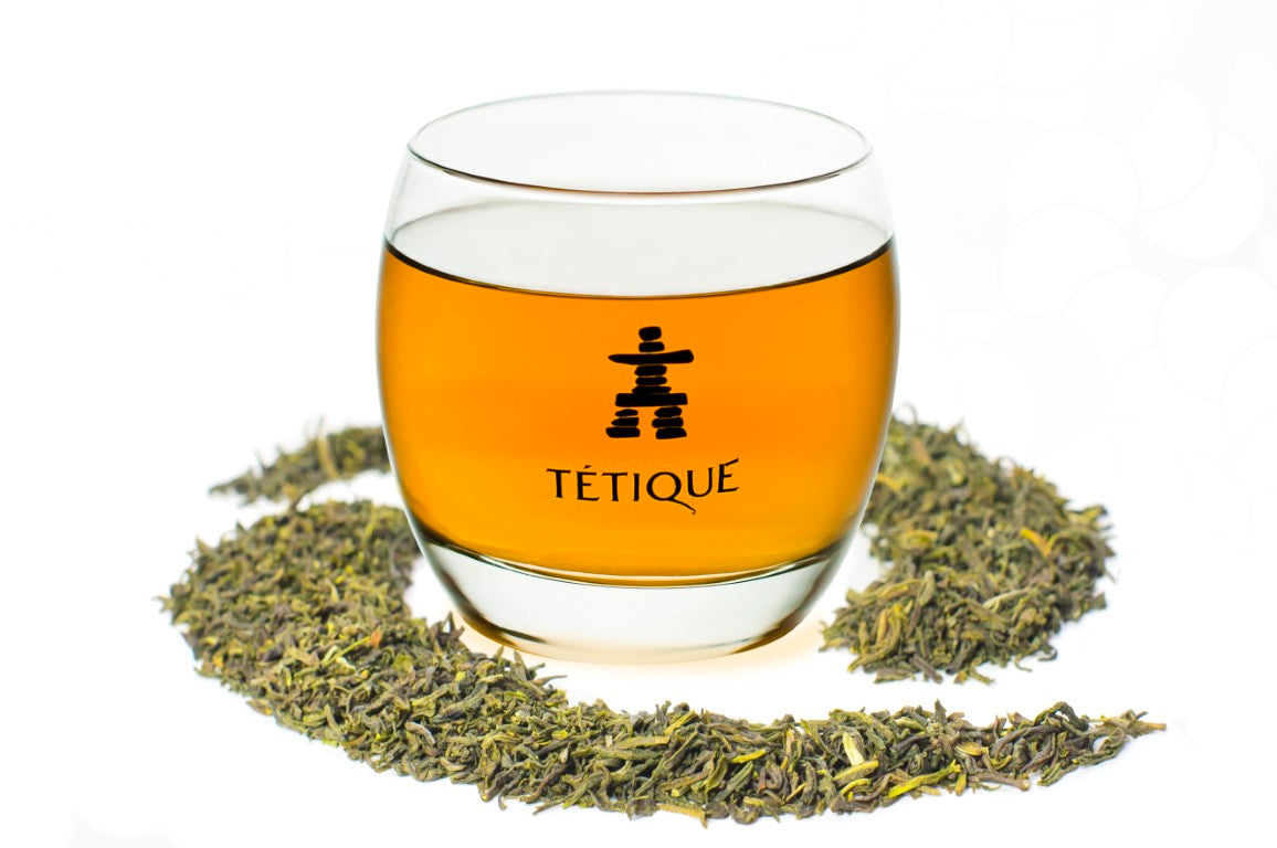 Té Verde Jazmín biológico a granel en vaso con fondo de hojas secas, de Tetique.