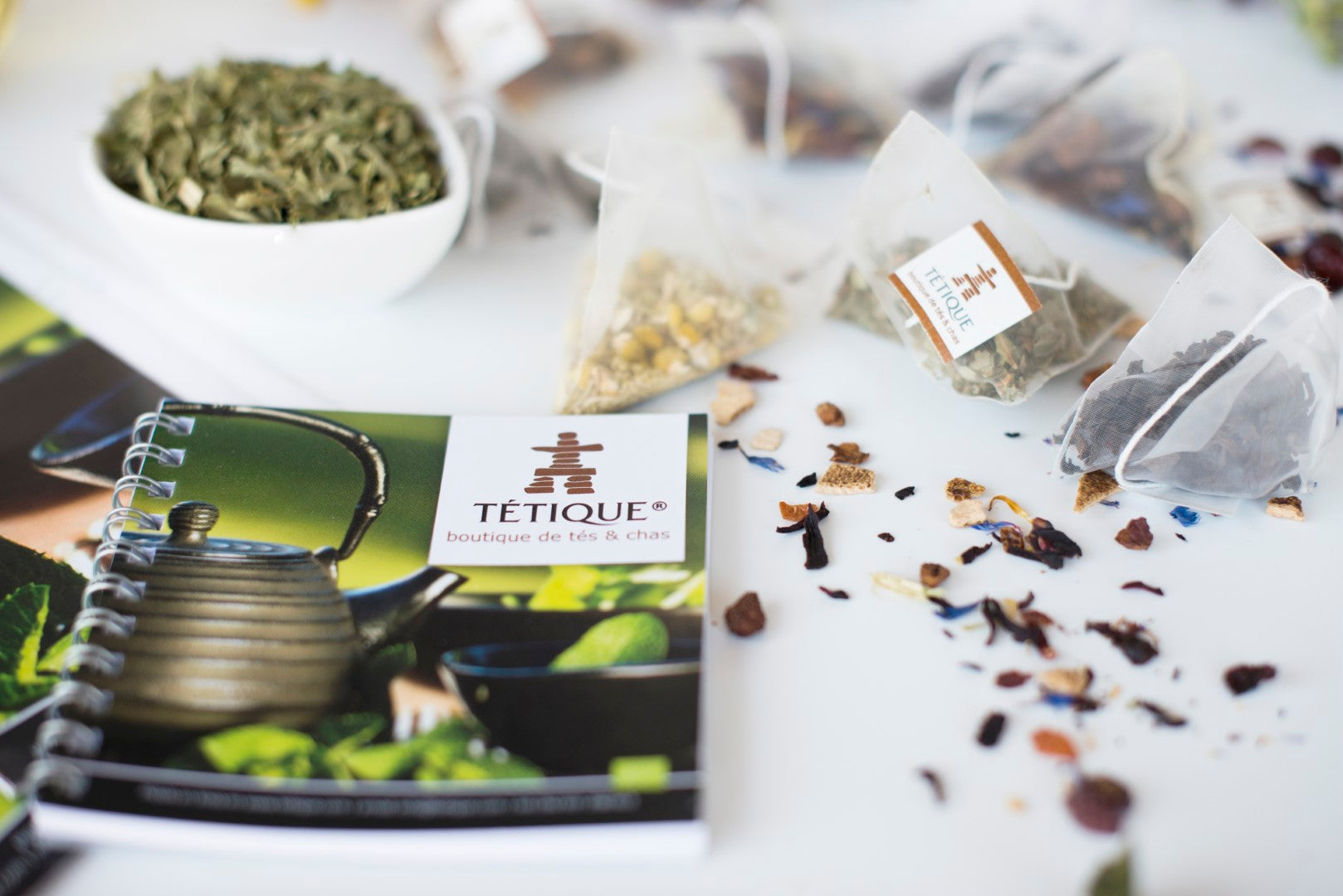 Menú de Tés Ecológicos de Tétique con variedad de tés, hojas secas y accesorios de té sobre una mesa.